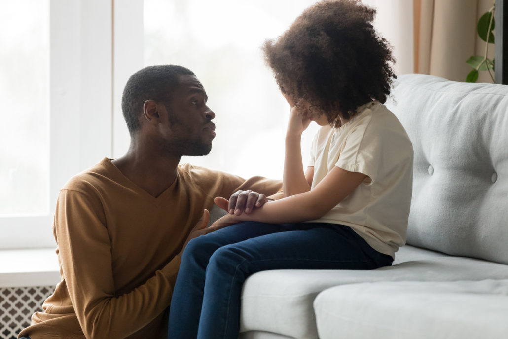 Loving dad comforting crying foster child by trying to listen to her.